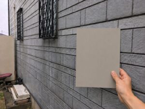 川越市の外壁塗装で大きな色見本を外壁に当てて確認する様子